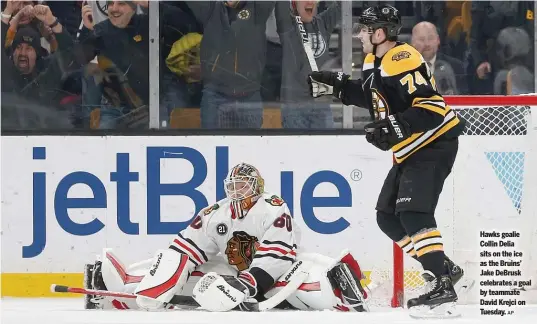  ?? AP ?? Hawks goalie Collin Delia sits on the ice as the Bruins’ Jake DeBrusk celebrates a goal by teammate David Krejci on Tuesday.