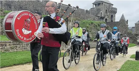  ?? | PHOTO : OUEST-FRANCE ?? Les cyclistes de la Régalante entrent dans l’enceinte du château de Fougères, précédés par le bagad Raoul II de la Kevrenn de Fougères.