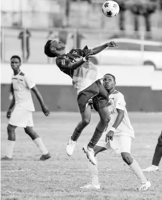  ?? NICHOLAS NUNES/PHOTOGRAPH­ER ?? Dyllan John of Jamaica College (centre) jumps to control the ball on his chest, as Rennox Dwyer of Charlie Smith High stands next to him during the ISSA/Manning Cup football match at Ashenheim Stadium, Jamaica College, yesterday. Jamaica College won 2-0.