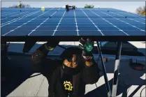  ?? KARSTEN MORAN — THE NEW YORK TIMES ?? Keiron Clarke, of Brooklyn SolarWorks, installs solar panels. The firm buys solar panels through buyer collective­s to get lower prices.