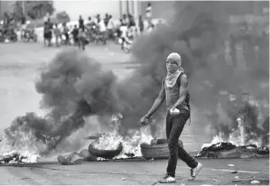  ??  ?? SEORANG penunjuk perasaan berjalan berhampira­n sekatan berapi semasa bertempur dengan polis di Port-au-Prince baru-baru ini pada hari kesembilan protes anti-Moise di Haiti. — Gambar AFP