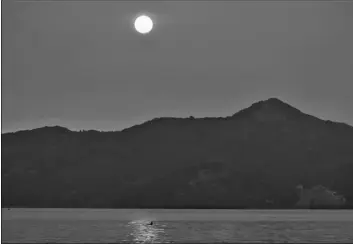  ?? AP Photo/Eric Risberg ?? A rower goes past Angel Island and the sun rising behind in smoke from wildfires on Wednesday in Sausalito, Calif.