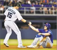  ?? Eric Espada / Getty Images ?? Brian Anderson of the Marlins, left helps up J.D. Davis of the Mets after an inning-ending double play in the seventh inning at Marlins Park on Sunday in Miami.