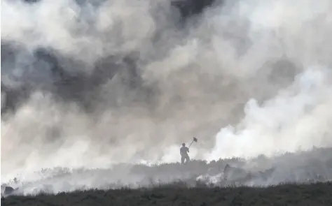  ?? — Reuters ?? A firefighte­r battles fire on a moor above Carrwood on Wednesday.