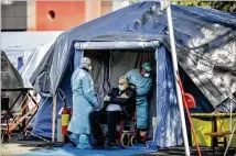  ?? CLAUDIO FURLAN/LAPRESSE VIA AP ?? An elderly patient is attended to Tuesday in an emergency structure set up to ease procedures outside a hospital in Brescia, in northern Italy. The country is the European epicenter for the coronaviru­s, which has claimed 631 lives in Italy.