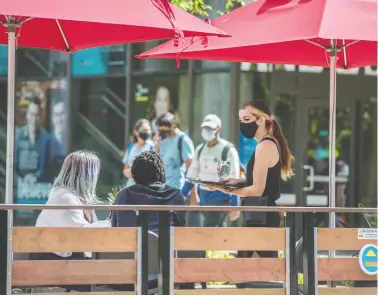  ?? PETER J THOMPSON / NATIONAL POST ?? A server takes diners' orders at a Toronto patio on Tuesday. The pandemic has given people pause for thought on the
question of gratuities; some eateries have adopted no-tipping policies in a bid to make workplaces more equitable.