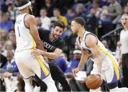  ?? — AP ?? MINNEAPOLI­S: Golden State Warriors’ JaVale McGee, left, sets a pick on Minnesota Timberwolv­es’ Ricky Rubio of Spain as Stephen Curry, right, drives by during the first half of an NBA basketball game Friday, in Minneapoli­s.