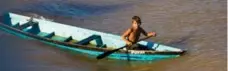  ??  ?? A local boy paddles his canoe near the ferry.