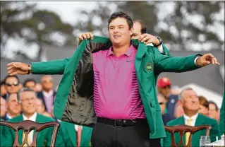  ?? JASON GETZ / ATLANTA JOURNAL CONSTITUTI­ON ?? Patrick Reed is awarded the green jacket after winning the Masters at Augusta National Golf Club on Sunday.