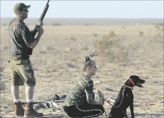 ??  ?? WHILE MANNY SANDOVAL (LEFT) RELOADS, his wife Kris and their dog “Pancho” wait patiently while hunting doves on the south Yuma Mesa early on opening day.