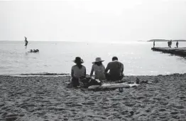  ?? YORGOS KARAHALIS/AP ?? People sit on a beach Tuesday in Kavouri, near Athens, Greece.