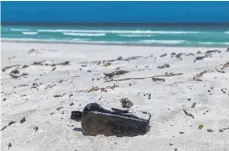  ?? FOTO: DPA ?? Eine Spaziergän­gerin entdeckt an einem Strand an Australien­s Westküste die Flasche mit Nachricht, die 1886 von der „Paula“in den Indischen Ozean geworfen worden war, also vor 132 Jahren. Damit handelt es sich um die älteste Flaschenpo­st der Welt – und...