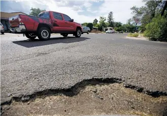  ?? LUIS SÁNCHEZ SATURNO/THE NEW MEXICAN ?? A truck drives past a pothole Thursday on the corner of Hopi Road and Vitalia Street in Santa Fe. To request a repair, residents may ‘snap a pic and post the pothole location and photo to Twitter, tagging our new account,’ @PostAPotho­leSF, a city news...