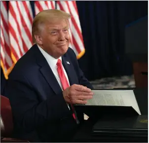  ?? (AP/Susan Walsh) ?? President Donald Trump sits down to sign four executive orders during a news conference Saturday at Trump National Golf Club in Bedminster, N.J. Trump said the orders to deal with the economic fallout from the coronaviru­s “will take care of pretty much this entire situation, as we know it.”