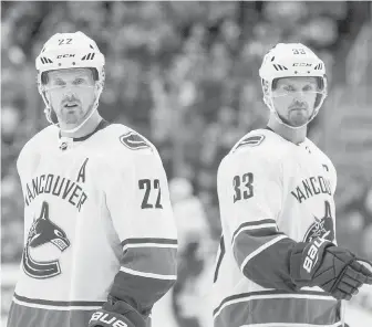  ?? THE CANADIAN PRESS ?? Vancouver Canucks’ Daniel Sedin, left, and Henrik Sedin skate past each other against the Edmonton Oilers during their NHL game in Edmonton on Saturday.