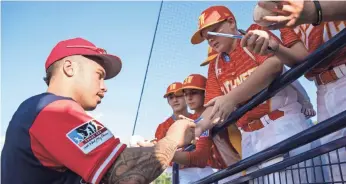  ??  ?? The Cardinals’ Kolten Wong signs autographs for Little League players before Sunday’s game.