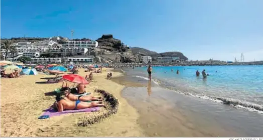  ?? JOSÉ MARÍA RODRÍGUEZ / EFE ?? Algunos turistas disfrutan de la playa de Puerto Rico, en el municipio grancanari­o de Mogán.