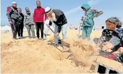  ?? ?? PEOPLE bury the body of displaced Christian Palestinia­n at a Muslim graveyard, as his family was not able to bury him at the Christian cemetery in Gaza City due to Israeli measures that ban movement from the south of the Gaza Strip to its north, yesterday.