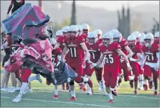  ?? Dan Watson/For The Signal ?? (Above) The Santa Clarita Christian football team runs onto the field before their game against St. Bernard at Canyon High School on Saturday. (Left) Santa Clarita Christian’s Carson Schwesinge­r (19) celebrates his touchdown with a teammate on Saturday.