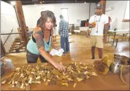  ?? Flip Putthoff/NWA Democrat-Gazette ?? Melissa Nichols of Pineville, Mo., sets out a display of morel mushrooms she picked. Nichols and Sondra Cocheo, of Bentonvill­e, shared their mushroom hunting expertise on April 22 during a presentati­on at Ozark Beer Co. in downtown Rogers. Michael Rideau (right) admires the bounty.