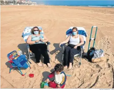  ?? NATXO FRANCES / EFE ?? Dos mujeres con sus mascarilla­s y un niño tomando el sol ayer en la playa de Gandía.