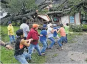  ?? Guiseppe Barranco / Beaumont Enterprise ?? Friends and family help pull a fallen tree from atop a Beaumont home after Cindy blew through.