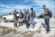  ?? Pedro Portal/El Nuevo Herald/TNS ?? Members of two groups of Cuban migrants from Matanzas — one with 19 people, the other with 12 — stand in the sun on the side of U.S. 1 in the Middle Keys island of Duck Key Monday morning. By noon, they said they have been standing there waiting to be picked up by U.S. Border Patrol agents since arriving in two rustic vessels at 2:30 a.m. on Jan. 2.