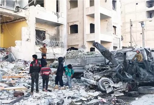  ??  ?? People look at the damage in the aftermath of an explosion at a base in an opposition-held area of the northweste­rn Syrian city of Idlib on Monday. (AFP)