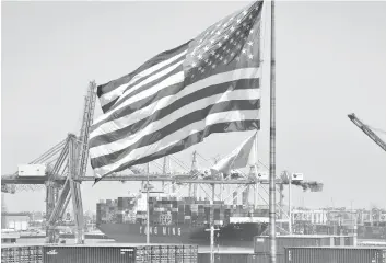  ?? Photo — AFP ?? The US flag flies over a container ship unloading it’s cargo from Asia, at the Port of Long Beach, California.