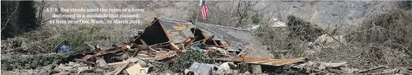  ??  ?? A U.S. flag stands amid the ruins of a home destroyed in a mudslide that claimed 44 lives near Oso, Wash., in March 2014.