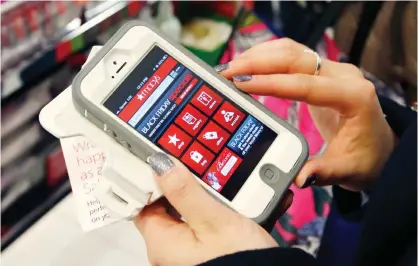  ?? — AP ?? BOSTON: In this Friday, Nov. 23, 2012, file photo, Tashalee Rodriguez, of Boston, uses a smartphone app while shopping at Macy’s in downtown Boston. For the first time, analysts predict more than half of online traffic to retailer sites will come from...