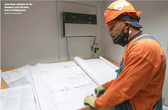  ?? BRIAN RICH/ SUN- TIMES ?? Jason Reed, a plumber for the Plumbers Local 130 union, looks at building plans.