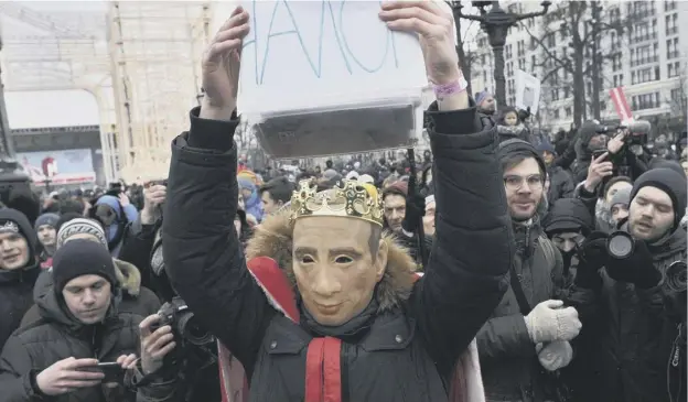  ?? PICTURE: AP ?? 0 A protester wearing a mask depicting Russian President Vladimir Putin holds up a sign reading ‘tax’ as he attends a rally in Moscow