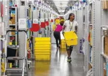  ?? STAFF PHOTO BY DOUG STRICKLAND ?? Workers fill yellow totes with merchandis­e in the pick mod area of the Amazon Fulfillmen­t Center in Enterprise South Industrial Park on Wednesday, Aug. 2, 2017, in Chattanoog­a.