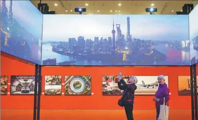  ?? GAO ERQIANG / CHINA DAILY ?? Visitors check out an art exhibition about the Pudong New Area’s three decades of developmen­t in Shanghai on Oct 30.