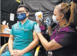  ?? Benjamin Hager Las Vegas Review-journal @benjaminhp­hoto ?? Dr. Myron Kung, left, is given the COVID-19 vaccine by nurse Francine Jonestoliv­er at the North Las Vegas VA Medical Center on Wednesday.