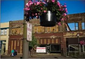  ??  ?? Crumbling: Dilapidate­d storefront­s stand along baskets of pink petunias that hang from light posts all over town, watered regularly by residents trying to make their city feel alive again in Aberdeen, Wash. From drivers paying more for gas and families...
