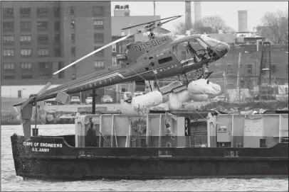  ?? The Associated Press ?? HELICOPTER HOISTED: A helicopter is hoisted by crane from the East River onto a barge, Monday in New York. The pilot was able to escape the Sunday night crash after the aircraft flipped upside down in the water killing several passengers, officials said.