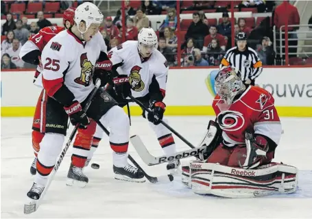  ?? GERRY BROOME/THE ASSOCIATED PRESS ?? Carolina Hurricanes goalie Dan Ellis (31) deflects the puck as the Senators’ Chris Neil (25) and Colin Greening (14) look on during the first period of Friday night’s game in Raleigh, N.C. In the end, the Sens would go down in defeat after knocking off...