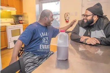  ?? MICHAEL BRYANT/PHILADELPH­IA INQUIRER ?? Will Ridley, left, shares a moment with his caregiver, Nicholas Smith, at the dinner table of Will’s home.