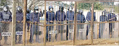  ??  ?? OSSU Police Officers manning the Lomahasha Police Station gate. ( LEFT) PUDEMO President Mlungisi Makhanya raises his fist before addressing the youth standing on top of a van, while next to him is Lomahasha Youth Leader Siboniso Mkhabela obscuring Lomahasha MP Ndumiso Masimula behind him.