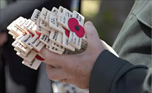  ?? AP Photo/Virginia Mayo ?? Wooden crosses with names of WWII dead are held prior to being laid for the Portsmouth Trust group by British expatriate Steven Oldrid during D-Day ceremonies at the local war cemetery June 6 in Benouville, Normandy, France. Due to coronaviru­s measures many relatives and veterans will not make this years 76th anniversar­y of D-Day. Oldrid will be bringing it to them virtually as he places wreaths and crosses for families and posts the moments on his facebook page.