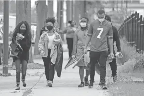  ?? MIKE DE SISTI / MILWAUKEE JOURNAL SENTINEL ?? From left, Valencia Patton, Tanasia Shaw, Adrian Perkins, Devon Curtis, behind, and Kenneth Webber, members of the National Panhelleni­c Conference, head down King Drive to clean up damage June 1. The MMAC announced a program to help damaged businesses.