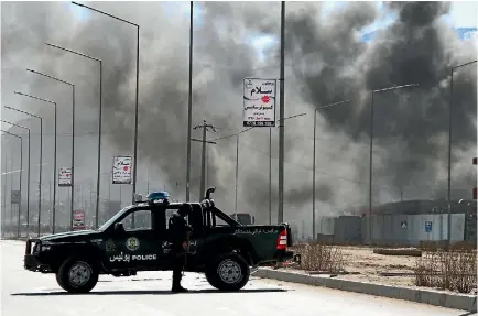  ?? PHOTO: GETTY IMAGES ?? Afghan security officials take up positions as smoke rises after a terrorist attack, claimed by the Taliban, on a military base in Kabul.