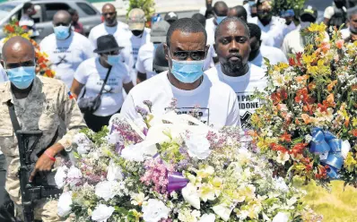  ?? AP ?? Pierre Gary Bernadotte, a member of President Jovenel Moise’s political party, carries flowers to a spot outside the presidenti­al palace in memory of the late president in Port-au-Prince, Haiti yesterday.