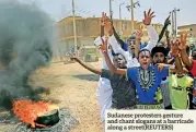  ??  ?? Sudanese protesters gesture and chant slogans at a barricade along a STREET(REUTERS)