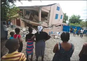  ?? Dieu Nalio Chery/AP ?? Quake: Residents stand looking at a collapsed school damaged by a magnitude 5.9 earthquake the night before, in Gros Morne, Haiti, Sunday. Emergency teams worked to provide relief in Haiti on Sunday after the quake killed at least 11 people and left dozens injured.
