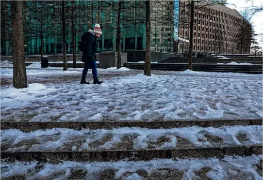  ?? PHOTOS BY CRAIG F. WALKER/GLOBE STAFF ?? Berna Kaya (above) navigated an ice-covered path near the Government Center MBTA Station on her way to work Thursday.