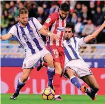  ??  ?? Atletico Madrid’s Yannick Ferreira Carrasco (C) vies with Real Sociedad’s Asier Illarramen­di (L) and Carlos Martinez (R) during their Spanish La Liga match at the Anoeta stadium yesterday. –