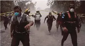  ?? AGENCIES PIX ?? Policemen helping people evacuate in the village of El Porvenir, Guatemala, after the Fuego volcano (right) erupted on Sunday.